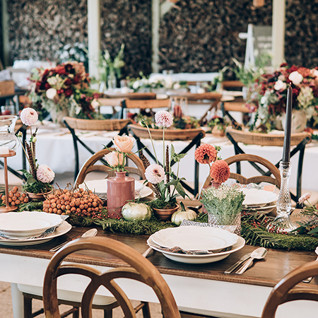 An elegant rustic table set up for an event with flowers, candles, and place settings.